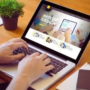Hands typing on a laptop showing a web design interface with “Best UX Design” on screen, representing accessible website development work