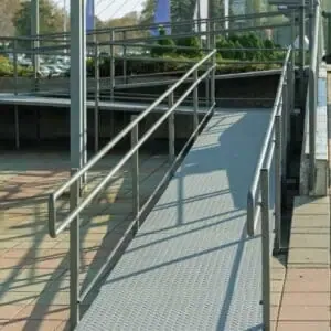 Sturdy metal wheelchair ramp with handrails, designed for ADA and California Title 24 compliance outside a public access building