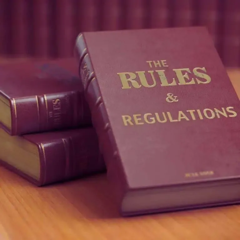leather-bound law books titled “Rules and Regulations” — symbolizing California’s strict ADA accessibility laws and the importance of understanding compliance requirements for public restrooms.
