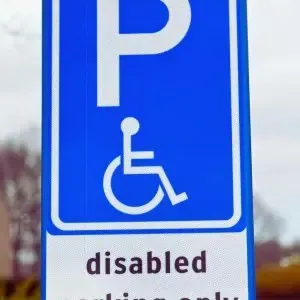 Blue and white disabled parking sign with wheelchair symbol and “disabled” text, illustrating proper ADA-compliant signage used in California parking lots.