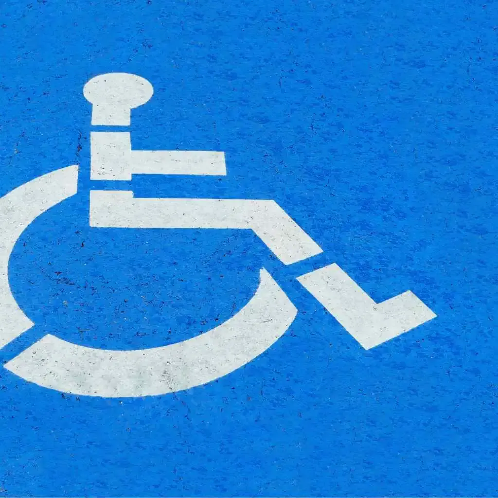 ADA-compliant wheelchair symbol painted on rough blue asphalt for reserved parking space in California